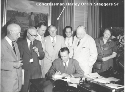 A group of people standing around a desk

Description automatically generated