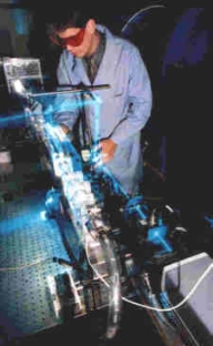 A person in a lab coat working on a machine

Description automatically generated