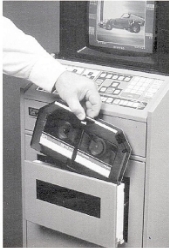 A hand putting a cassette into a machine

Description automatically generated
