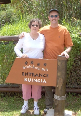 A person and person standing next to a sign

Description automatically generated